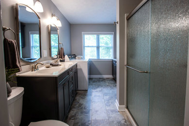 Inspiration for a mid-sized transitional master ceramic tile, beige floor and double-sink bathroom remodel in Cleveland with gray cabinets, a two-piece toilet, gray walls, an integrated sink, solid surface countertops, beige countertops and a built-in vanity