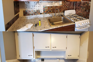 Example of a small single-wall kitchen design in New York with flat-panel cabinets, white cabinets, granite countertops, white backsplash, ceramic backsplash and multicolored countertops