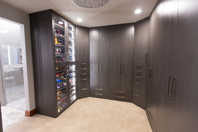 Mid-sized trendy gender-neutral carpeted and beige floor walk-in closet photo in Other with dark wood cabinets