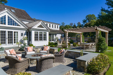 Huge backyard stone patio kitchen photo in New York with a gazebo