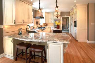 Kitchen pantry - mid-sized transitional l-shaped medium tone wood floor kitchen pantry idea in Philadelphia with a double-bowl sink, raised-panel cabinets, distressed cabinets, granite countertops, multicolored backsplash, stone tile backsplash, black appliances and an island