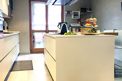 Immagine di una grande cucina moderna con lavello sottopiano, ante lisce, ante bianche, elettrodomestici neri, pavimento in gres porcellanato, pavimento grigio, top in superficie solida, paraspruzzi grigio, paraspruzzi in gres porcellanato e top bianco