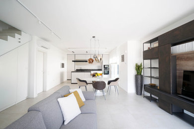 Immagine di un grande soggiorno design aperto con libreria, pareti bianche, pavimento in gres porcellanato, parete attrezzata e pavimento beige