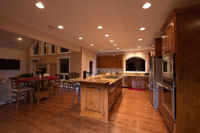 Inspiration for a large timeless l-shaped medium tone wood floor open concept kitchen remodel in Other with an undermount sink, raised-panel cabinets, dark wood cabinets, granite countertops, beige backsplash, ceramic backsplash, stainless steel appliances and an island