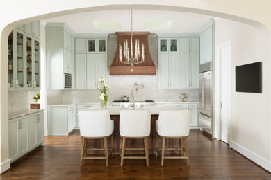 Open concept kitchen - mid-sized traditional u-shaped medium tone wood floor and brown floor open concept kitchen idea in Dallas with a farmhouse sink, recessed-panel cabinets, blue cabinets, quartzite countertops, white backsplash, ceramic backsplash, stainless steel appliances, an island and white countertops