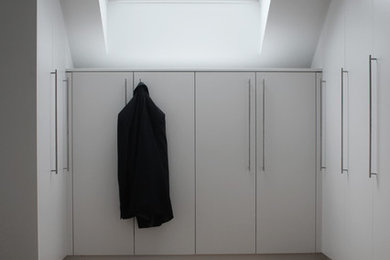 Großer, Neutraler Klassischer Begehbarer Kleiderschrank mit flächenbündigen Schrankfronten, weißen Schränken, braunem Holzboden und braunem Boden in Köln