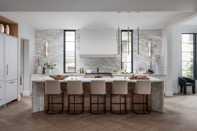 Eat-in kitchen - large l-shaped light wood floor eat-in kitchen idea in Other with flat-panel cabinets, white cabinets, marble countertops, marble backsplash and an island