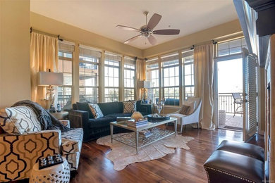 Example of a mid-sized transitional open concept dark wood floor and brown floor family room design in Denver with beige walls, a stone fireplace, a standard fireplace and a tv stand