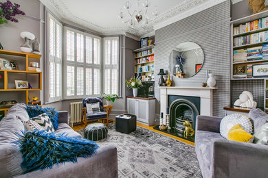 Example of a mid-sized eclectic enclosed light wood floor living room design in London with gray walls and a tv stand