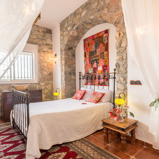 Mediterranes Schlafzimmer mit weißer Wandfarbe und braunem Boden in Sonstige