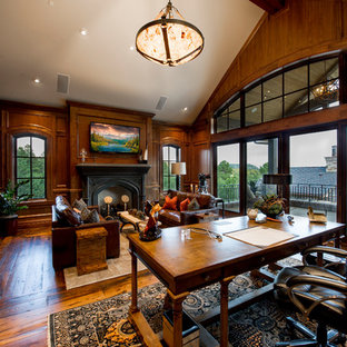 Inspiration för ett stort rustikt hemmabibliotek, med mellanmörkt trägolv, ett fristående skrivbord, bruna väggar, en standard öppen spis, en spiselkrans i trä och brunt golv