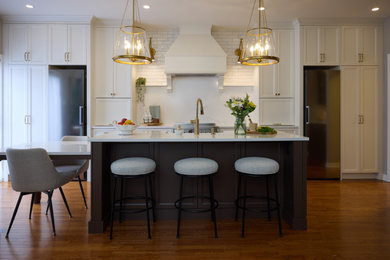 Example of a large transitional single-wall medium tone wood floor and brown floor eat-in kitchen design in Ottawa with white backsplash, stainless steel appliances, an island, white countertops, a farmhouse sink, quartz countertops, quartz backsplash, shaker cabinets and brown cabinets