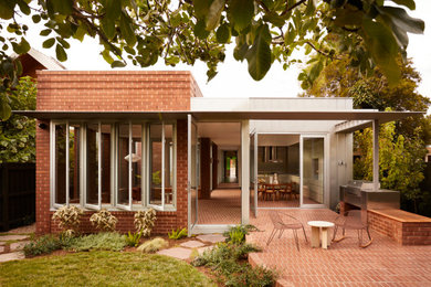 Inspiration for a large midcentury one-storey brick red house exterior in Melbourne with a flat roof, a metal roof and a grey roof.