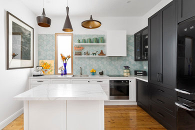 Inspiration for a mid-sized transitional l-shaped kitchen in Melbourne with an undermount sink, shaker cabinets, black cabinets, green splashback, porcelain splashback, medium hardwood floors, with island, brown floor and grey benchtop.
