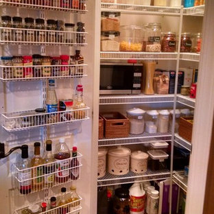 This is an example of a small transitional l-shaped kitchen pantry in DC Metro with an undermount sink, raised-panel cabinets, medium wood cabinets, granite benchtops, beige splashback, stone tile splashback, black appliances, dark hardwood floors and with island.