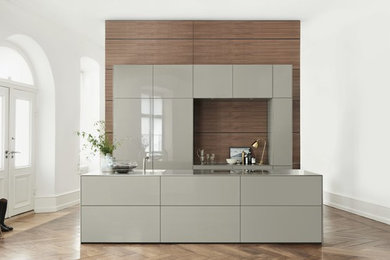 Inspiration for a large contemporary single-wall open plan kitchen in Munich with flat-panel cabinets, stainless steel benchtops, with island, brown splashback, dark hardwood floors and grey cabinets.