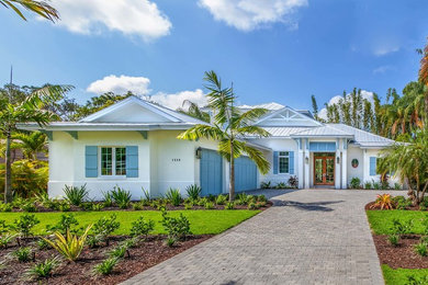 Inspiration for a beach style two-storey stucco white house exterior in Tampa with a gable roof and a metal roof.