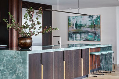 This is an example of a large contemporary galley open plan kitchen in Sydney with an undermount sink, flat-panel cabinets, dark wood cabinets, quartzite benchtops, green splashback, stone slab splashback, stainless steel appliances, with island and green benchtop.