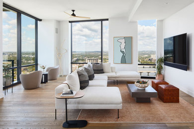 Example of a trendy open concept medium tone wood floor and brown floor living room design in Austin with white walls and a wall-mounted tv