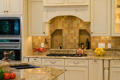 Elegant enclosed kitchen photo in Boston with beige cabinets, granite countertops, beige backsplash, paneled appliances and an island
