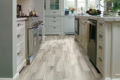 Example of a large farmhouse single-wall porcelain tile and beige floor enclosed kitchen design in Phoenix with an undermount sink, recessed-panel cabinets, white cabinets, marble countertops, stainless steel appliances and an island