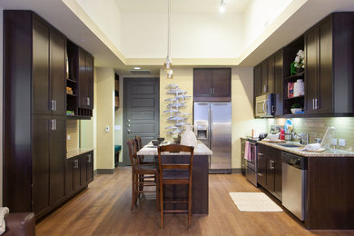 Eat-in kitchen - large contemporary l-shaped medium tone wood floor eat-in kitchen idea in Austin with an undermount sink, recessed-panel cabinets, beige backsplash, subway tile backsplash, stainless steel appliances and an island