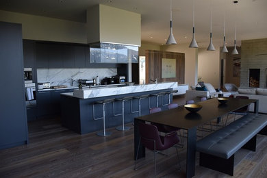 Open concept kitchen - large contemporary l-shaped dark wood floor and brown floor open concept kitchen idea in Vancouver with an undermount sink, flat-panel cabinets, gray cabinets, marble countertops, stone slab backsplash, stainless steel appliances, an island and gray backsplash