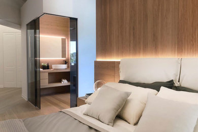 Foto di una camera da letto stile loft design di medie dimensioni con pareti bianche, parquet chiaro, pavimento marrone e boiserie