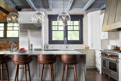 Inspiration for a country l-shaped kitchen in Atlanta with a farmhouse sink, recessed-panel cabinets, white cabinets, white splashback, stainless steel appliances, dark hardwood floors, with island, brown floor and grey benchtop.