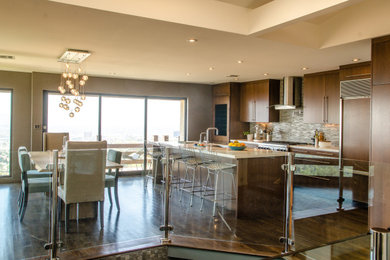 Example of a large dark wood floor kitchen design in Los Angeles with a farmhouse sink, flat-panel cabinets, dark wood cabinets, quartzite countertops, mosaic tile backsplash, stainless steel appliances and an island