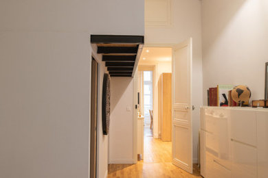 Idée de décoration pour une chambre mansardée ou avec mezzanine design de taille moyenne avec un mur blanc, parquet clair, aucune cheminée et un sol marron.