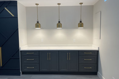 Example of a minimalist look-out vinyl floor, gray floor and wall paneling basement design in Detroit with a bar, beige walls and a standard fireplace
