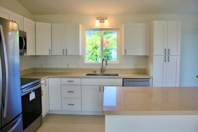 Eat-in kitchen - coastal l-shaped ceramic tile and beige floor eat-in kitchen idea in Hawaii with a drop-in sink, recessed-panel cabinets, white cabinets, quartz countertops, beige backsplash, stainless steel appliances, an island and beige countertops