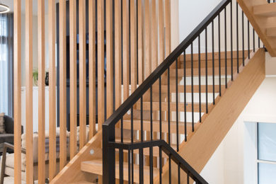 Large minimalist wooden floating open, wood railing and wall paneling staircase photo in Calgary