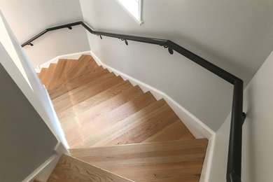 Diseño de escalera curva industrial con barandilla de metal, escalones de madera y contrahuellas de madera