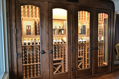 Mid-sized arts and crafts wine cellar in Sacramento with dark hardwood floors, storage racks and brown floor.