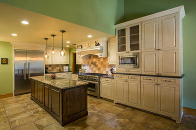 Mid-sized elegant l-shaped ceramic tile eat-in kitchen photo in Austin with a drop-in sink, raised-panel cabinets, beige cabinets, granite countertops, beige backsplash, stone tile backsplash, stainless steel appliances and an island