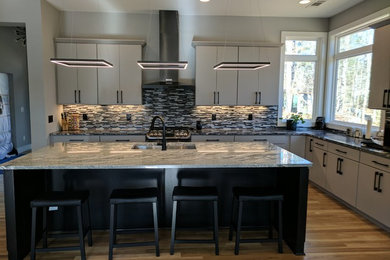 Modern l-shaped eat-in kitchen in Atlanta with an undermount sink, flat-panel cabinets, grey cabinets, granite benchtops, multi-coloured splashback, glass sheet splashback, stainless steel appliances, light hardwood floors and with island.