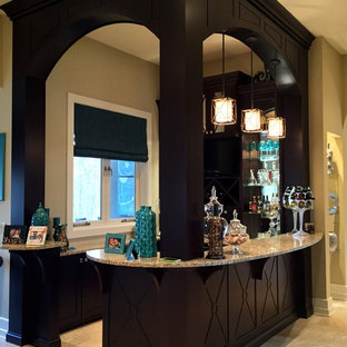 他の地域の大きいトラディショナルスタイルのおしゃれなウェットバー (フラットパネル扉のキャビネット、黒いキャビネット、御影石カウンター、トラバーチンの床、ベージュの床、アンダーカウンターシンク) の写真