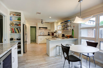Eat-in kitchen - mid-sized mid-century modern u-shaped porcelain tile eat-in kitchen idea in Houston with a farmhouse sink, shaker cabinets, white cabinets, granite countertops, white backsplash, subway tile backsplash, stainless steel appliances and a peninsula
