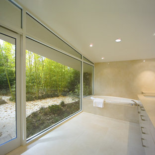 Idee per una grande stanza da bagno padronale moderna con lavabo sottopiano, ante lisce, ante bianche, vasca da incasso, pareti beige, pavimento in pietra calcarea e top in pietra calcarea