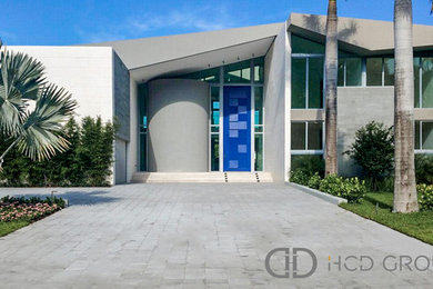 Large modern white two-story stone exterior home idea in Miami with a shed roof