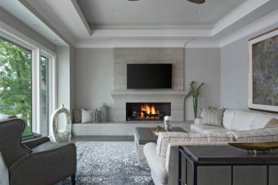 Inspiration for a large transitional formal and enclosed medium tone wood floor and gray floor living room remodel in Detroit with gray walls, a standard fireplace, a stone fireplace and a wall-mounted tv