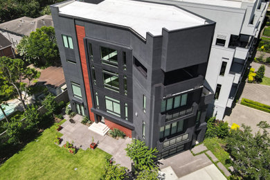 Huge modern black four-story stucco and clapboard exterior home idea in Houston with a white roof