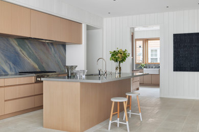 Example of a beach style single-wall porcelain tile and gray floor kitchen design in San Francisco with an undermount sink, flat-panel cabinets, light wood cabinets, multicolored backsplash, stainless steel appliances, an island and gray countertops