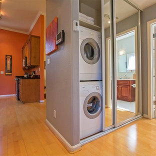 Small contemporary single-wall laundry cupboard in San Francisco with a stacked washer and dryer, grey walls and bamboo flooring.