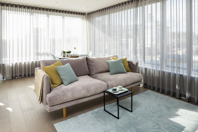 Design ideas for a small contemporary open plan living room in London with white walls, light hardwood flooring, no fireplace, a freestanding tv and grey floors.