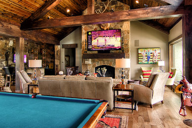 Game room - huge farmhouse open concept medium tone wood floor game room idea in Other with brown walls, a standard fireplace, a stone fireplace and a wall-mounted tv