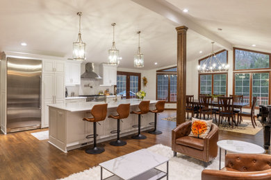 Inspiration for a mid-sized transitional galley medium tone wood floor, brown floor and vaulted ceiling open concept kitchen remodel in Cleveland with a farmhouse sink, shaker cabinets, white cabinets, quartz countertops, white backsplash, ceramic backsplash, stainless steel appliances, an island and white countertops