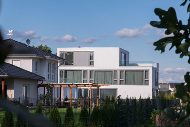 Großes, Dreistöckiges Modernes Einfamilienhaus mit Putzfassade, weißer Fassadenfarbe und Flachdach in Berlin